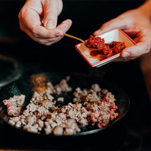 Hackfleisch in Pfanne wird angebraten und gewürzt