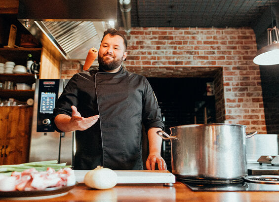 Daniel Parzen steht hinter Kochinsel und bereitet lächelnd die Ramen-Zutaten vor